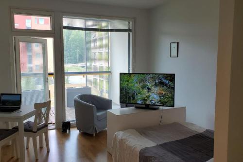 a bedroom with a bed and a television and a chair at Studio, 9 min walk to train+15 min city or airport in Vantaa