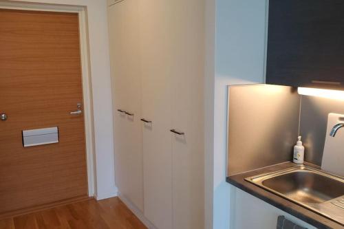 a small kitchen with a sink and a door at Studio, 9 min walk to train+15 min city or airport in Vantaa