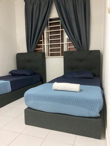 a bedroom with two beds with blue sheets and a window at ABSYAR HOMESTAY SELASIH in Putrajaya