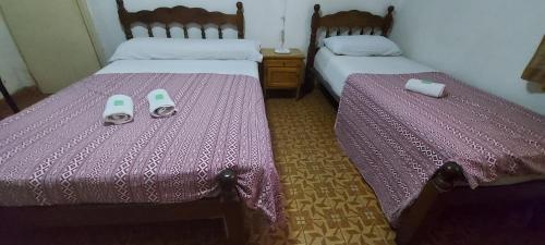2 camas en una habitación con sábanas moradas y zapatillas en Hotel Central en Buenos Aires
