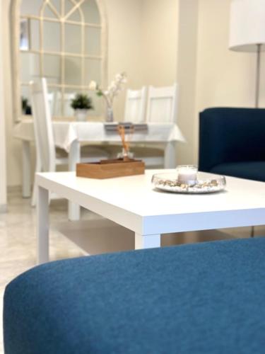 a white dining room table with a blue chair and a white table with a blue at Apartamento Puerta Cerrada in Écija