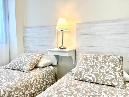 a bedroom with two beds and a table with a lamp at Apartamento Puerta Cerrada in Écija