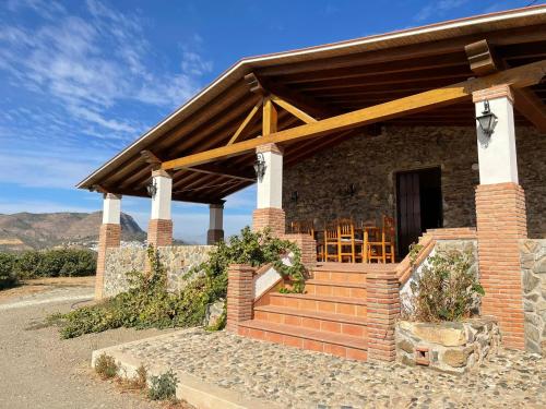 une maison en briques avec un toit en bois et des escaliers dans l'établissement Casa rural Los Caballos Finca Los Pelaeros Alora Caminito del Rey, à Alora