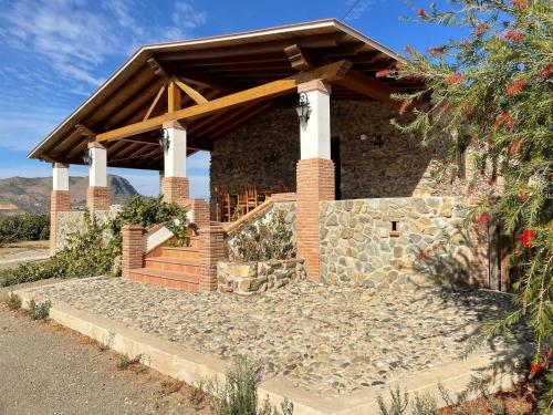 ein Steinhaus mit einem Holzdach und einem Steinsteg in der Unterkunft Casa rural Los Caballos Finca Los Pelaeros Alora Caminito del Rey in Alora