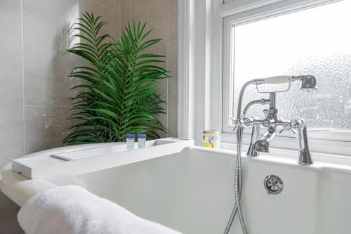 a white bath tub with a shower in a bathroom at 1 Min to Beach, 8 Guests, Garden, Snug, Parking - Azure House in Bournemouth