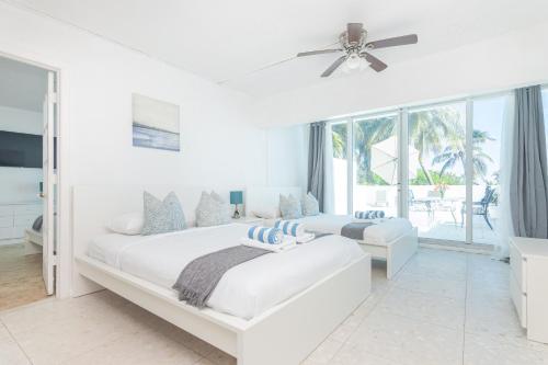 a white bedroom with a large bed and a ceiling fan at Girasole Rentals in Miami Beach