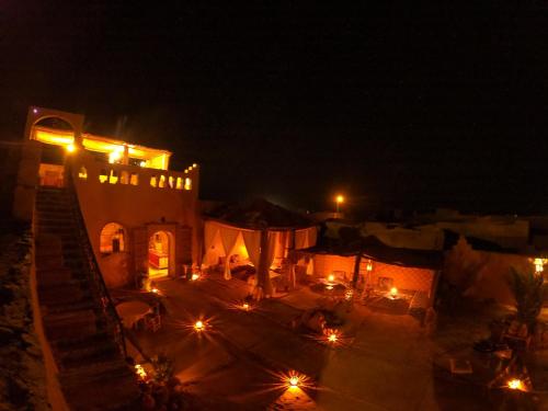 a night view of a building with lights at Auberge Kasbah Dar Sahara Tours in Mhamid