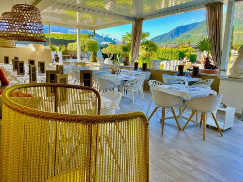 un restaurante con mesas y sillas con montañas al fondo en Schlosshof Charme Resort – Hotel & Camping, en Lana