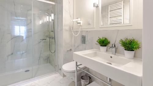La salle de bains blanche est pourvue d'un lavabo et d'une douche. dans l'établissement VacationClub – Baltic Park Fort Apartament G.402, à Świnoujście