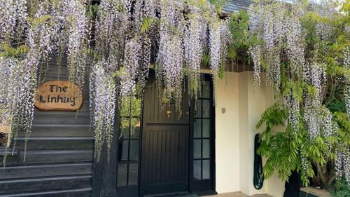 un edificio con glicinas colgando de un lado. en Linhay -Farm Cottage, en Sidmouth