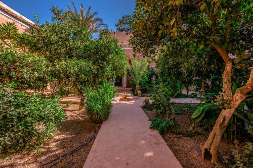 a walkway through a garden with trees and a bench at Prestige du Souss in Oulad Berhil