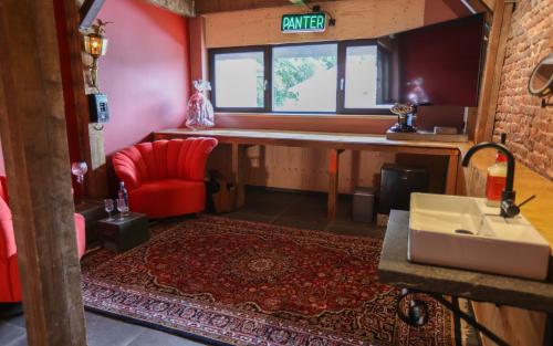 een woonkamer met een rode stoel en een wastafel bij VET - Bed & Breakfast in Beek