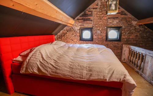 a bedroom with a red bed in a brick wall at VET - Bed & Breakfast in Beek