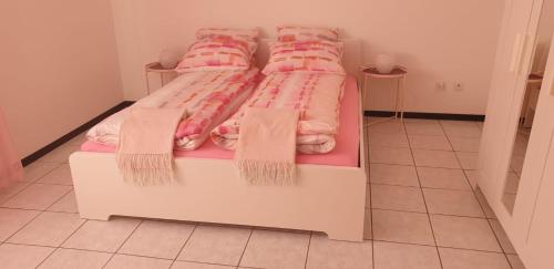 una camera da letto con letto e lenzuola e cuscini rosa di Alloggio Corina a Cadenazzo