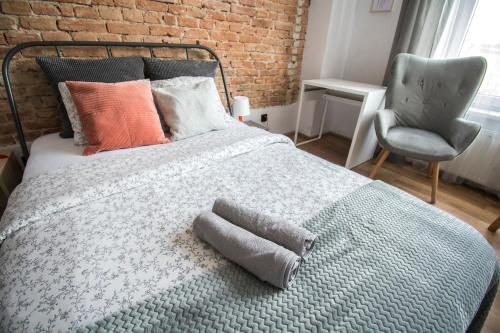 a bedroom with a bed with a pillow and a chair at LION apartments - SILVER in Kraków