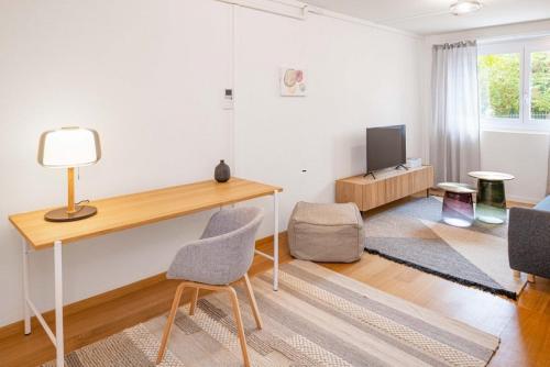 a living room with a desk and a tv at one bedroom apartment in trendy Zurich West in Zürich
