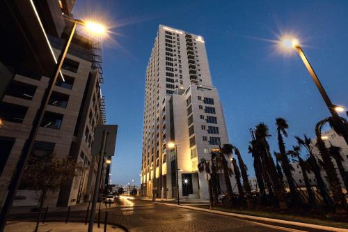 a tall white building on a city street at night at Abdali Views Apartments in Amman