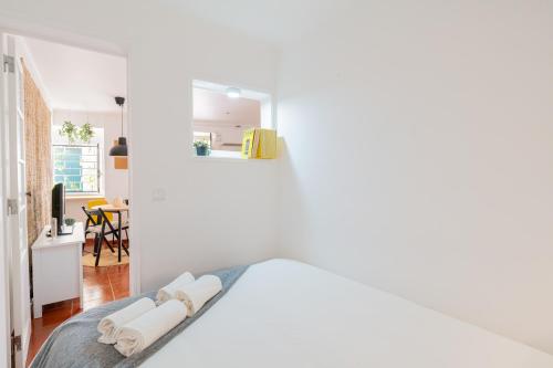 a white bedroom with a bed and a living room at Alfama Nest in Lisbon