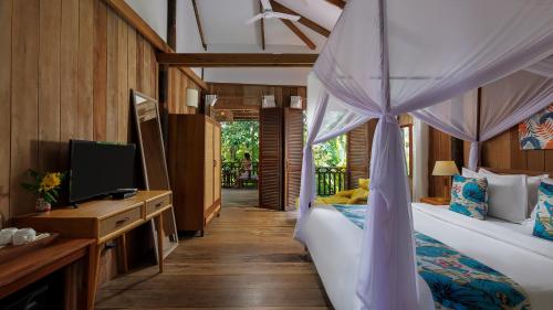 a bedroom with a canopy bed and a tv in it at Dontrei Villa Angkor in Siem Reap