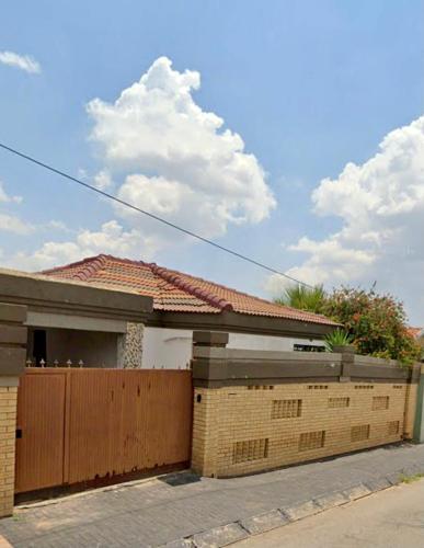 a house with a wooden gate and a fence at Colourful modern home in Soweto