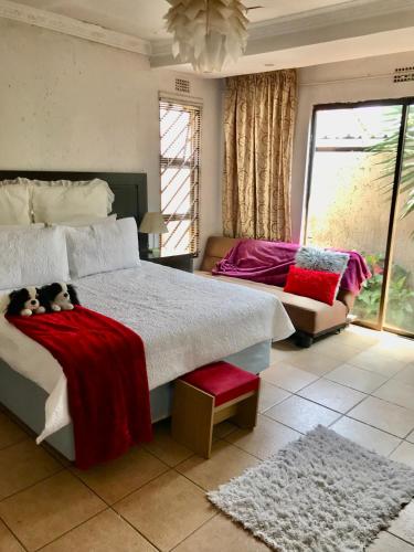 um quarto com uma cama grande e um cobertor vermelho em Colourful modern home em Soweto