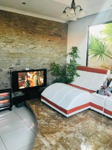 a bedroom with a large bed and a flat screen tv at Colourful modern home in Soweto