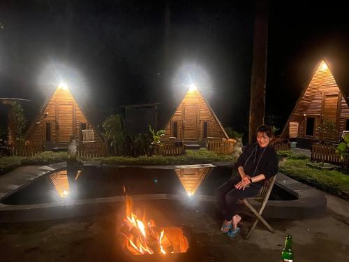 a man sitting in a chair in front of a fire at Triangle House and hot spring in Kintamani
