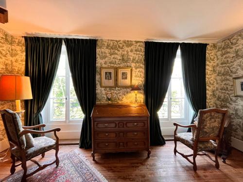 PichenyにあるChâteau de Pichenyの椅子2脚、ドレッサー、窓2つが備わる客室です。