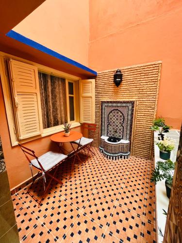 a patio with a table and chairs and a fireplace at Joli appartement avec patio, parking et toit terrasse Nice apartment with patio, parking and rooftop in Marrakesh