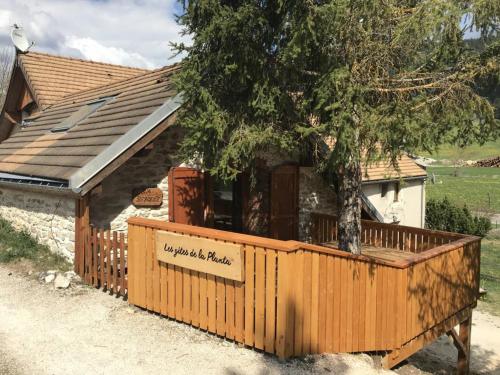 una recinzione di legno di fronte a una casa con un albero di Gites de la Planta a Le Bouilly