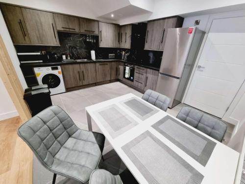 eine Küche mit Tisch und Stühlen und einem Kühlschrank in der Unterkunft LMK, spacious 1 bedroom Ground floor Apartment, EV charger, Free parking Wi-fi, Great location in Belfast