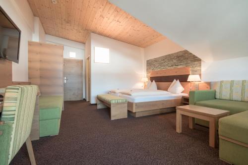 um quarto de hotel com uma cama e um sofá em Hotel Alpenwelt Superior em Flachau