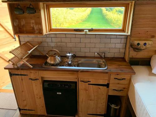 a kitchen with a sink and a window above it at Orchard retreat off grid shepherds huts in Dorset in Dorchester
