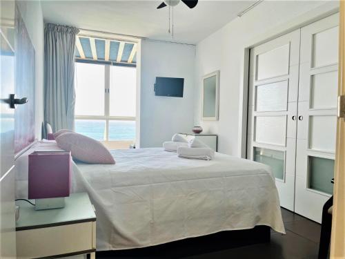 ein weißes Schlafzimmer mit einem großen Bett und einem Fenster in der Unterkunft Frente a playa Malagueta Miramar in Málaga
