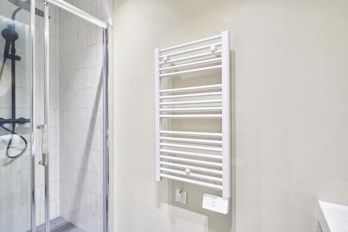 Un toallero blanco en un baño junto a una ducha. en Residence Le Marais Beaubourg by Studio prestige, en París