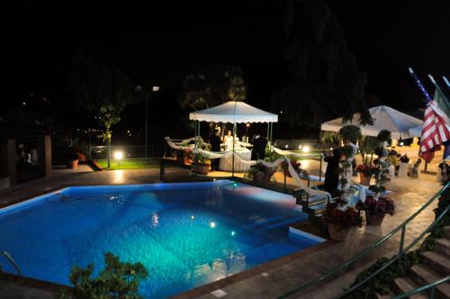 a swimming pool at night with people standing around it at Hotel Diecimare in Cava deʼ Tirreni