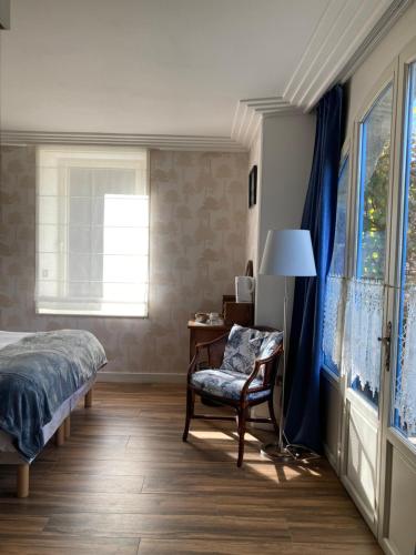 1 dormitorio con 1 cama, 1 silla y 1 ventana en Chambres d’hôtes Nordlys, en Pluneret