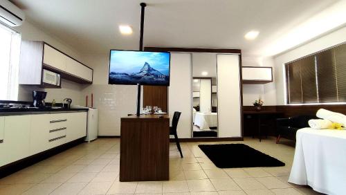 a kitchen with a flat screen tv on the wall at Lindos Studios Centro/Wifi/Garagem in Foz do Iguaçu