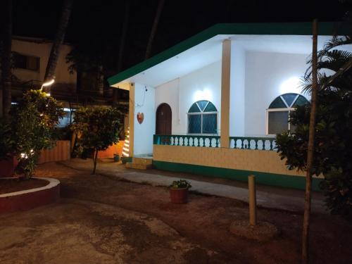 a small white house with a green roof at night at Rosetta Guesthouse in Anjuna