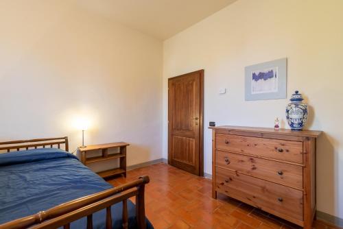 a bedroom with a bed and a wooden dresser at Villa La Tinaia Il Sole Verde in Bucine