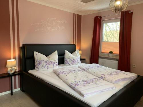 a large bed with purple and white sheets and pillows at Ferienhaus SweetDreams in Bad Sachsa