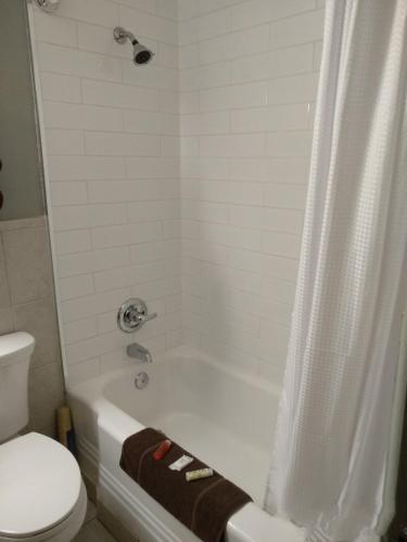 a bathroom with a tub and a toilet and a shower at Park Lane Motor Hotel Medicine Hat in Medicine Hat