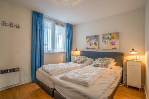 a bedroom with a large bed with blue curtains at Appartementencomplex Juliana 52 in De Koog
