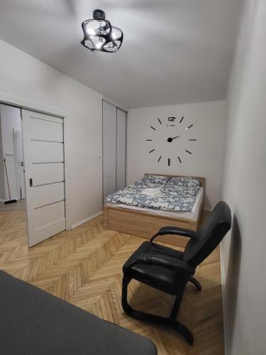 1 dormitorio con 1 cama y reloj en la pared en Apartament przy Lipowej en Białystok