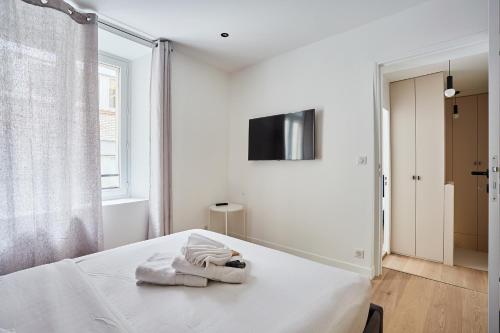 a white bedroom with a bed and a tv at Apartment Louvre Museum by Studio prestige in Paris