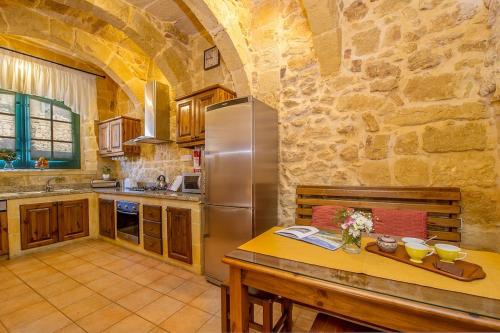 a kitchen with a stainless steel refrigerator and a table at Razzett Tuta Holiday Home in Kerċem