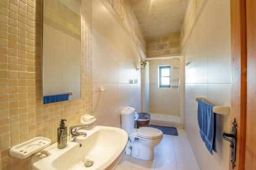 La salle de bains est pourvue d'un lavabo et de toilettes. dans l'établissement Razzett Tuta Holiday Home, à Kerċem