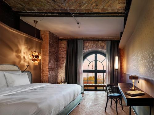 a bedroom with a bed and a desk and a window at Telegraphenamt in Berlin