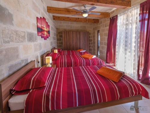 a bedroom with two beds with red striped sheets at Ta' Majsi Holiday Home in Xlendi