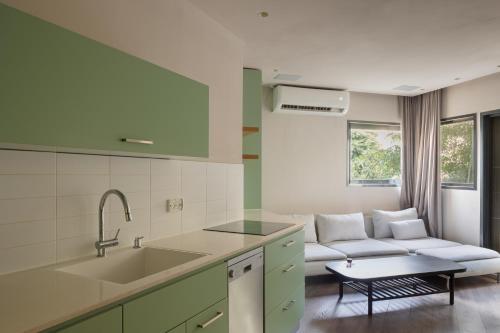 una cocina con armarios verdes y un sofá en una habitación en Perfect Studio near sea by TLV2RENT, en Tel Aviv